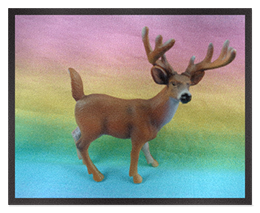 a small plastic toy deer on a rainbow cloth background